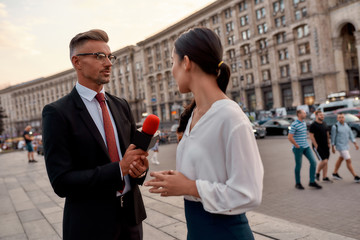 Professional reporter interviewing woman on urban street. Journalism industry, live streaming concept