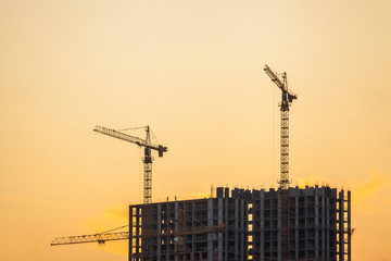 construction site with cranes against the background of bright evening clouds