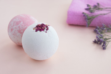 Obraz na płótnie Canvas Bath bombs, flowers and cotton towels on light background. Natural cosmetics and home spa concept. Close up, copy space