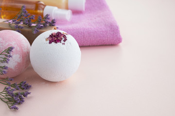 Bath bombs, flowers, cotton towels and bottles with cosmetic products on light background. Natural cosmetics and home spa concept. Close up, copy space