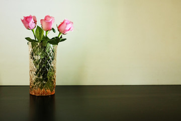 Three pink roses in glass vase on white background