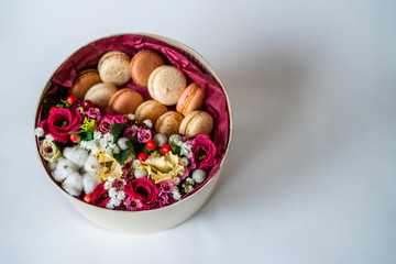 Gift or present with flower and french macaroons on grey background with copy space. Rustic style. Toned image.