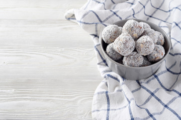 Energy balls with prunes, almond and coconut. Vegan raw food. White wooden background. Minimalism concept. Good nutrition diet.