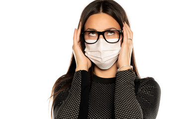 Beautiful young woman with headache and protective mask on her face