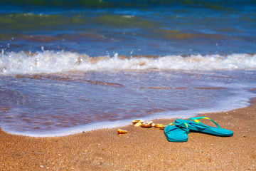Fototapeta na wymiar blue Slippers stand on the sand on the seashore