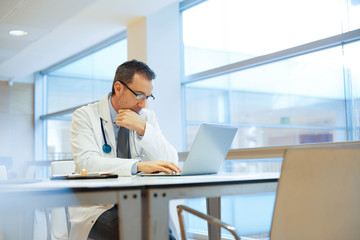 Doctor in hospital office working on laptop