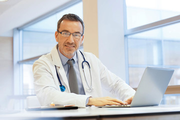 Doctor in hospital office working on laptop