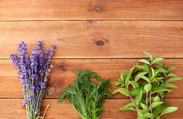 Fototapeta na wymiar gardening, ethnoscience and herbs concept - bunches of lavender, dill and peppermint on wooden background