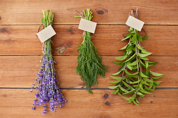 gardening, ethnoscience and herbs concept - bunches of lavender, dill and peppermint with name tags on wooden background