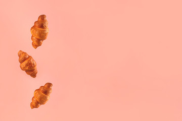Croissants flying on pink background. Levitation scene.