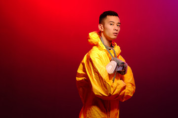 Asian man in a yellow suit of chemical protection and in a protective mask on a color trend color background. Concept Breaking Bad