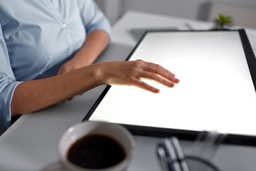 technology and people concept - hand on led light tablet or touch screen at night office