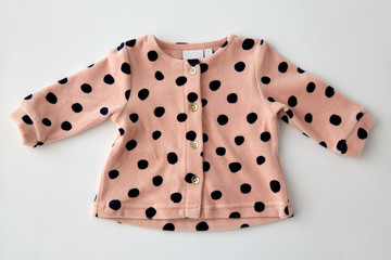 clothes, babyhood and clothing concept - pink cardigan for baby girl with dot print on white...