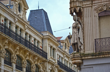 Fototapeta na wymiar Saint-Etienne, France - January 27th 2020 : Focus on the statue of a king at the corner of a building, in front of an another edifice.