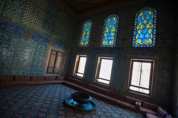Diagonal view of Islamic patterns covering a dark room with glowing stained glass windows