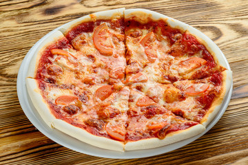 small pizza with tomatoes for children on a wooden background