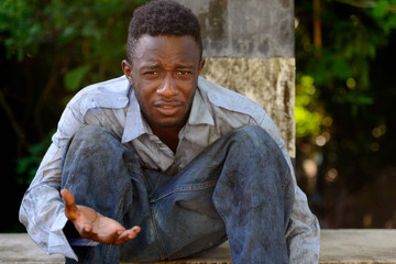 Young homeless African man begging on the bridge