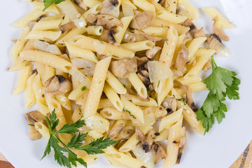 Cooked penne pasta with fried mushrooms and onions, top view