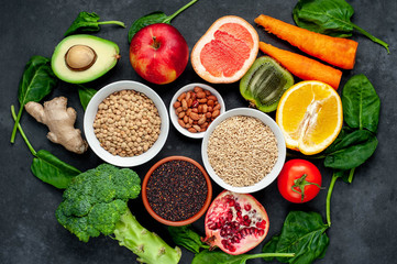 Selection of healthy food:  fruits, seeds, cereals, superfoods, vegetables, leafy vegetables on a stone background. Healthy food for humans