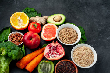 Selection of healthy food:  fruits, seeds, cereals, superfoods, vegetables, leafy vegetables on a stone background. Healthy food for humans. Copy space for your text.