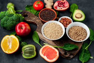 Selection of healthy food:  fruits, seeds, cereals, superfoods, vegetables, leafy vegetables on a stone background. Healthy food for humans