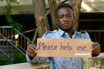 Young homeless African man with cardboard sign asking for help
