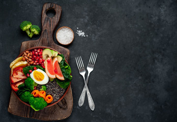 Fototapeta na wymiar Bowl of Buddha,quinoa, orange, avocado, grapefruit, tomato, pomegranate, spinach, carrots, broccoli, egg in a bowl on a stone background, with copy space for your text