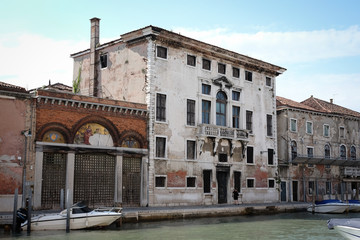 Fototapeta na wymiar vecchio palazzo dell'isola di Murano rovinato dal tempo con cielo blu e canale della laguna Veneta