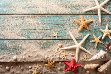 Seashell, starfish and beach sand on blue wooden background. Summer holiday concept. Top view.