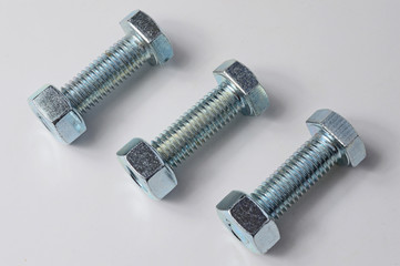 three bolts with nuts screwed on them. White background.