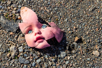 Old broken doll face on ground