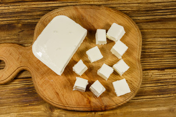 Feta cheese on cutting board on a wooden table. Top view