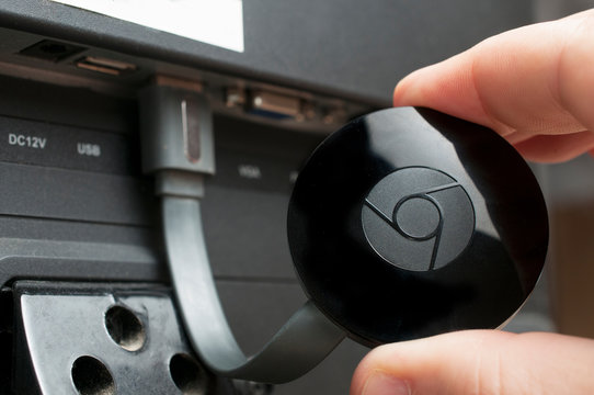 A man show a google chromecast device connected to a tv