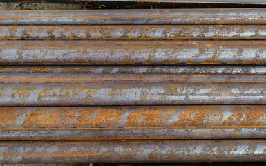 Racks of metal profiles. Metal is stored in an open warehouse. Wet and rusty on the street. Old grunge background made of rusty iron for shooting flatleys on the table