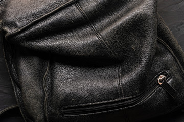 black background - old crumpled leather bag with zipper lock close-up