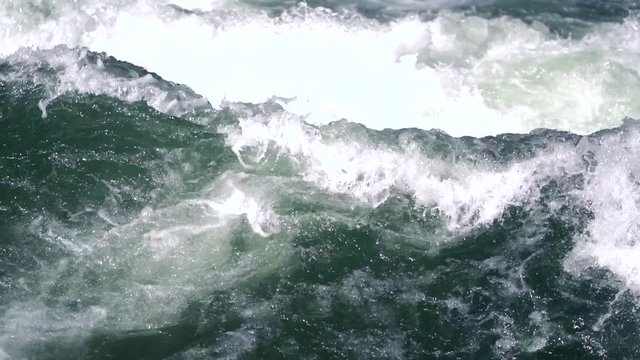 Wild waves at a fast rapids. Cold icy Eisbach in munich closeup. Brave people surf here in all seasons. Slow motion of strong waves in the river, can also illustrate ocean waves.