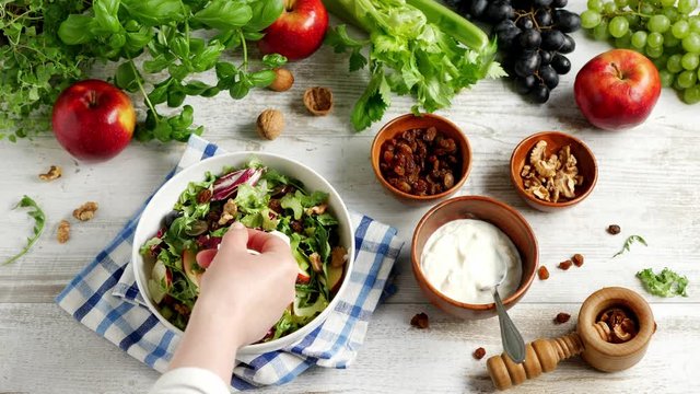 Waldorf Salad. Decorating the salad with basil. The chef lays a basil leaf with his hand.