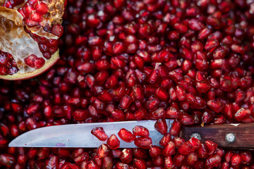 background of pomegranate seeds, juicy cut fruit. close- up of the knife.