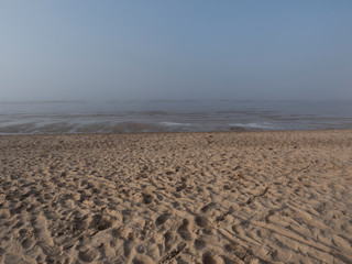 Footprints in the sand of the seashore. Light fog.