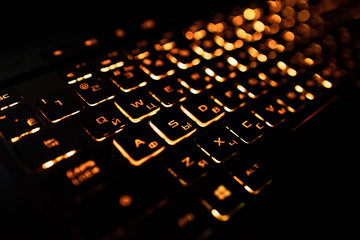 Computer keyboard with Russian and English layout. Backlit by neon light.