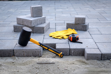The master in yellow gloves lays paving stones in layers. Garden brick pathway paving by...