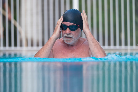 close up of pensioner man in the pool doing exercise alone swimming - active people and healthy and fit senior - lifestyle of active mature man
