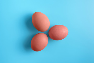 Three red easter eggs on blue surface. Colorful easter eggs decoration. Flat lay, top view. with copy space for text.