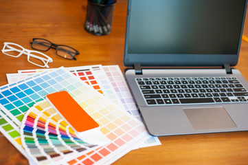 Graphic designer desk. Graphic designer laptop and color swatch examples.