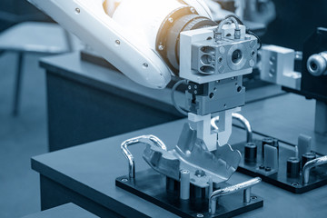 The robotic arm gripping the formed sheet metal parts from the setting jig to the conveyor belt in automotive factory. The hi-technology  material handing process in by robotics system.