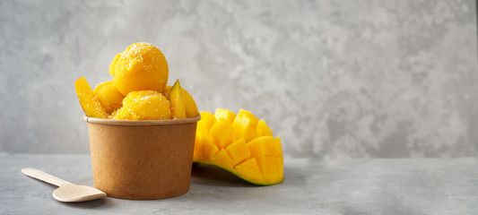 Refreshing mango ice cream in craft paper cup on gray background