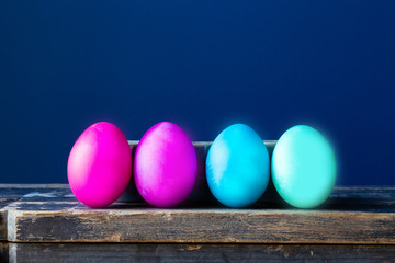 Dyed colorful easter eggs pastel colors near blue wall, modern neon colors spring concept