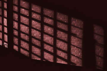Dark red quadratic shadow on a stonework wall illuminated by blood red light - concept dramatic contrast film noir mystic interior texture background surface structure window close up detail evening