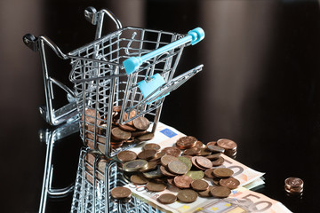 blue shopping cart with money. Reflected table. Dark background. Finance. Financial crisis. Banking system. Economic problem. Inflation. Money printing.