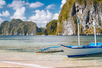 Plakat El Nido. Close up of traditional filippino boat on shore with Pinagbuyutan island in background. Palawan, Bacuit archipelago, Philippines